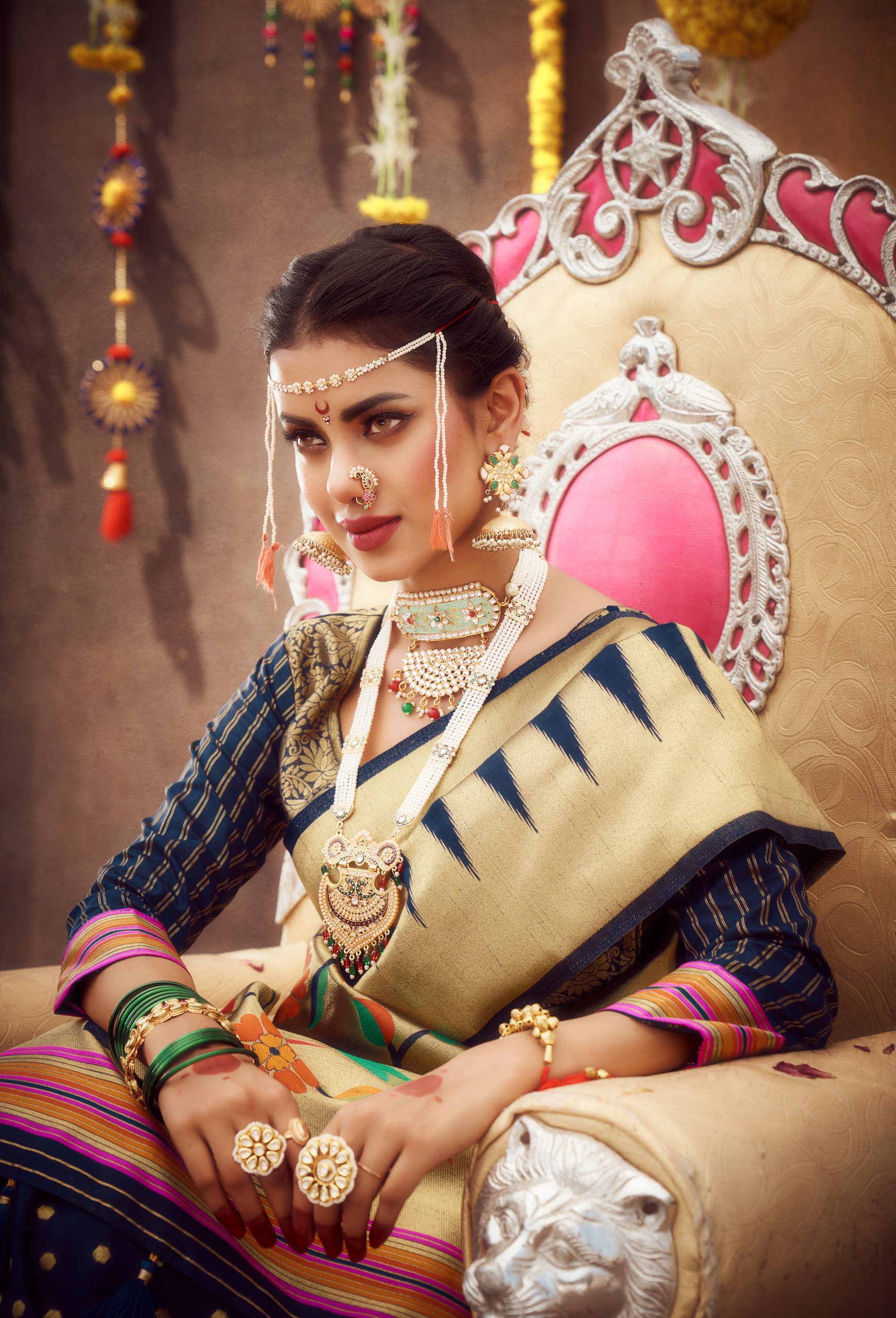 woman wearing royal looking saree and sitting on a throne looking confident